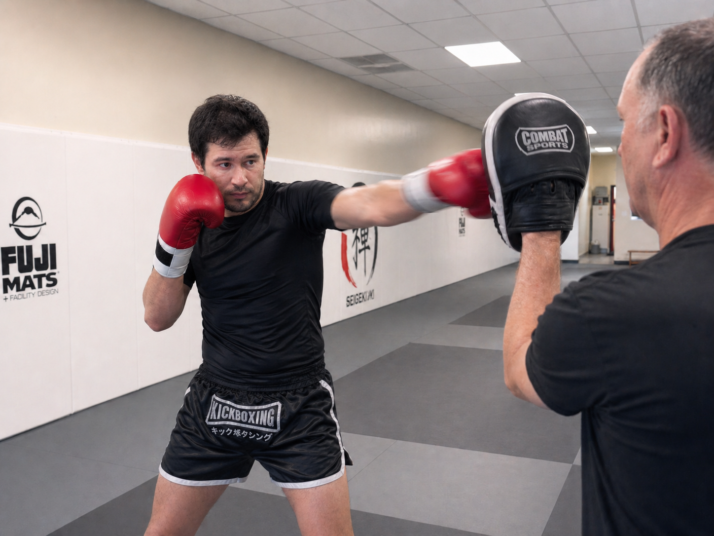 Adult kickboxing student firing combos on the focus mitts after one month at ZEN