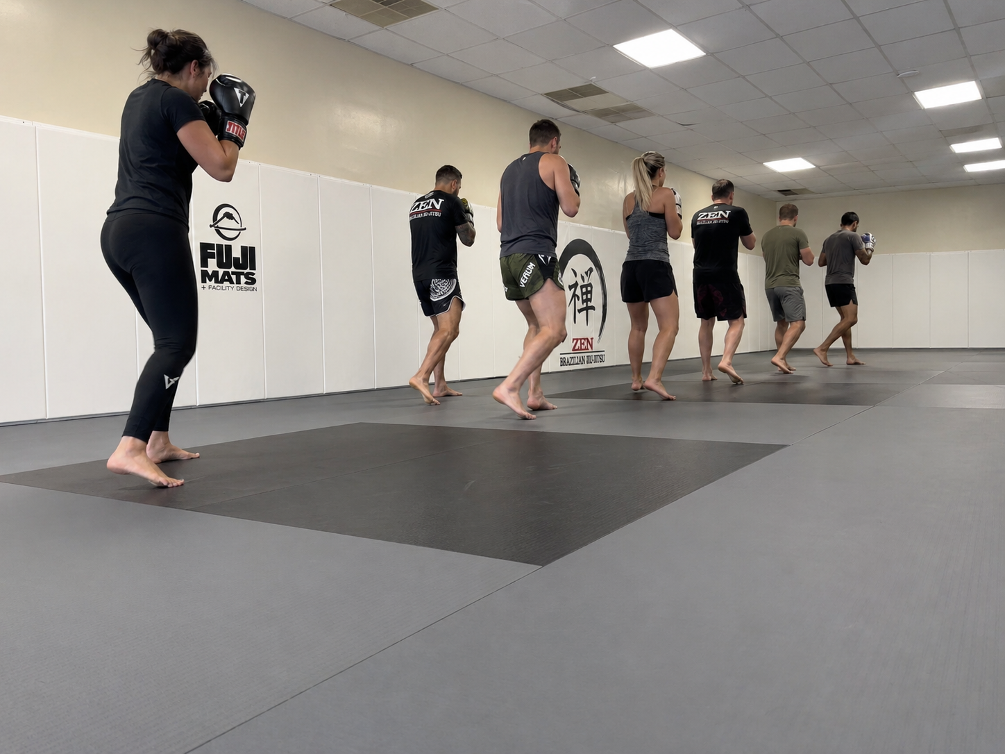 Adult kickboxing class drilling footwork on the mats at ZEN