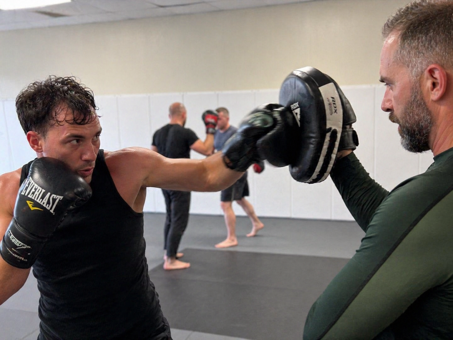 Coach holding focus mitts during a kickboxing class at ZEN